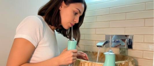 Female model using green Avelora Pro water flosser in modern bathroom