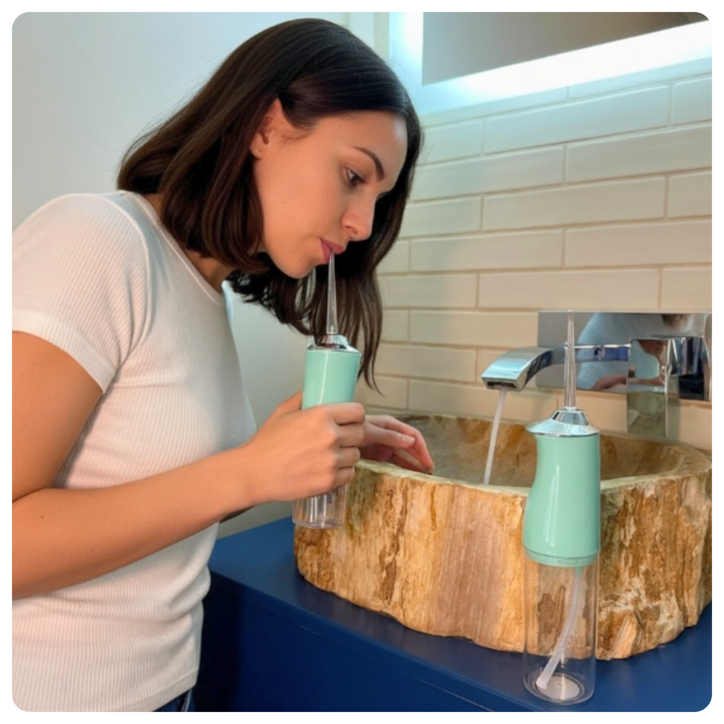 colour:green Female model using green Avelora Pro water flosser in modern bathroom